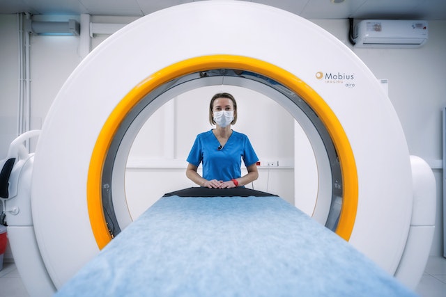 MRI tech in front of MRI machine for travel radiology tech jobs