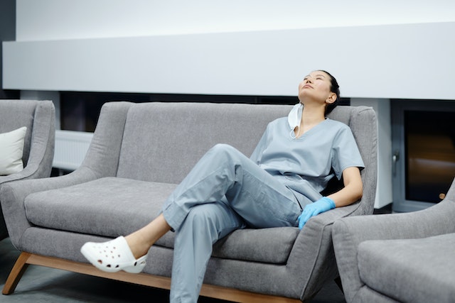 Travel nurse relaxing on couch practicing self-care during allied health job