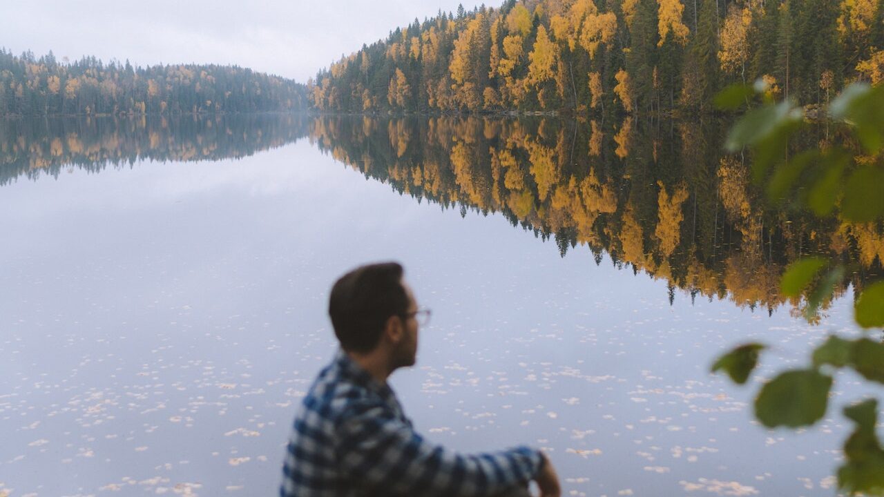 man sitting by autumn lake after finding travel respiratory therapist jobs